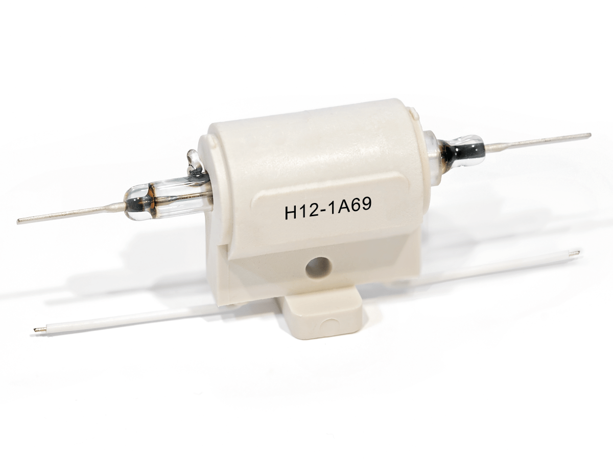 A white ceramic H Series Reed Relay electrical component labeled H12-1A69 with two metal terminal leads on each side and a mounting base underneath, isolated on a white background. by Standex Detect