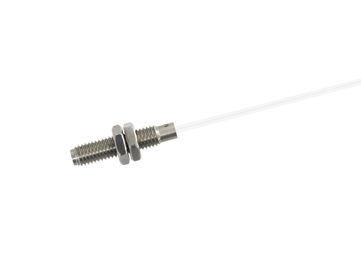 A close-up of a stainless steel MK11 Reed Sensor with a hexagonal nut and washer, attached to a thin, clear or white cable on a white background. by Standex Detect