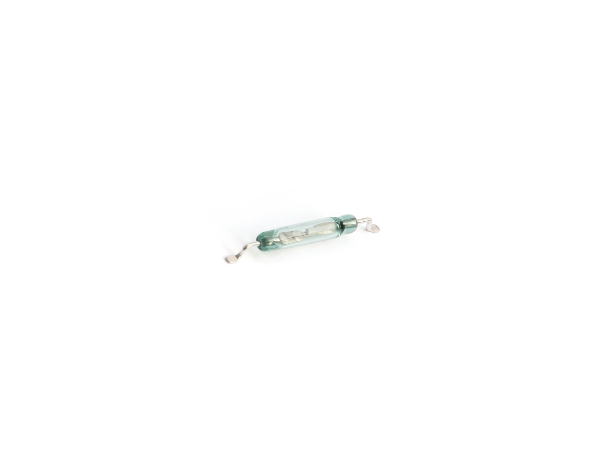 A small MK23-87 glass reed switch with two metal leads on each end, isolated on a white background. by Standex Detect